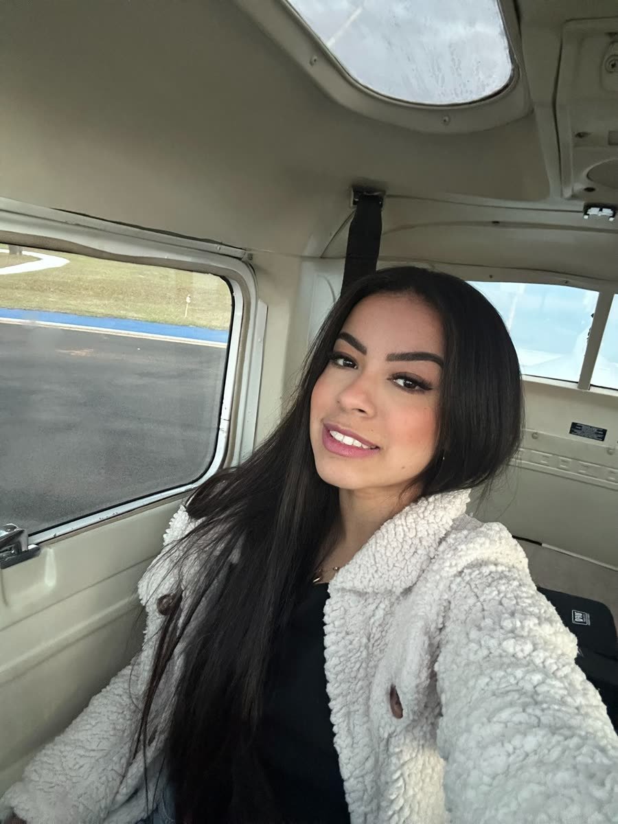 Micaely dentro do avião, sorrindo